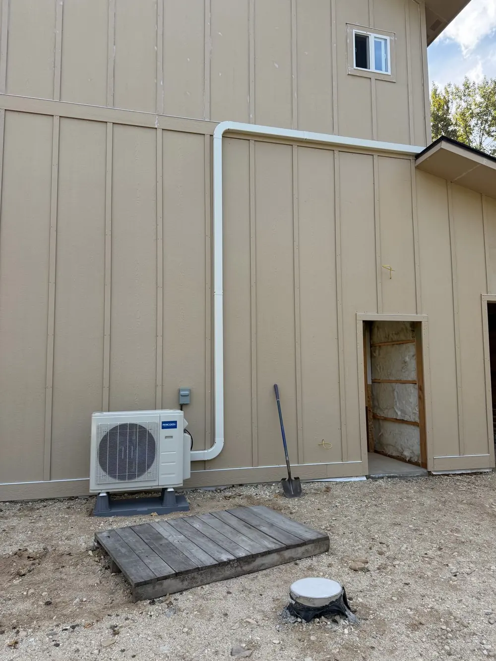 Mini split outdoor condenser on its pad, with the line-set cover tied into the back of the unit