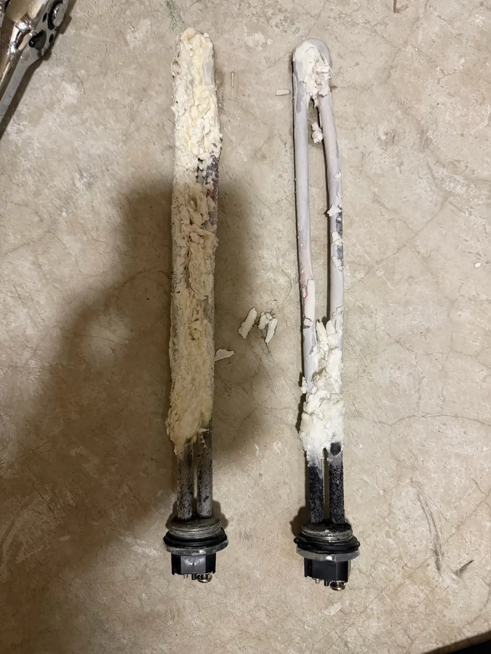 Two heavily scaled electric water heater heating elements